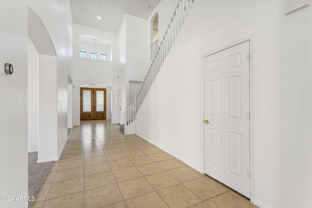 tiled entryway with a high ceiling and french doors