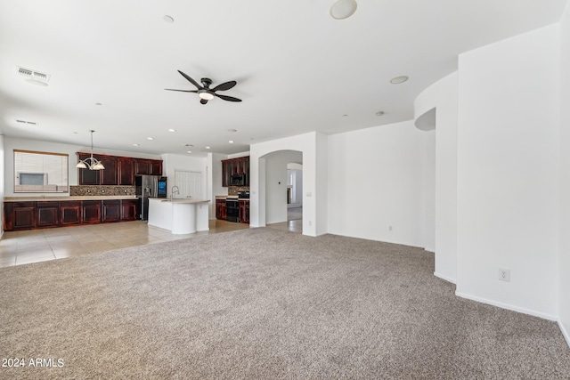 unfurnished living room featuring light carpet, sink, and ceiling fan