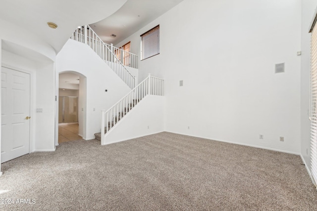 unfurnished living room featuring a high ceiling and carpet floors