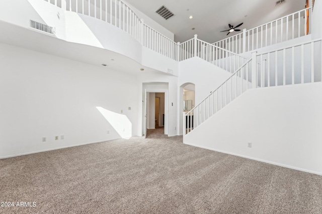 unfurnished living room with ceiling fan, a high ceiling, and carpet