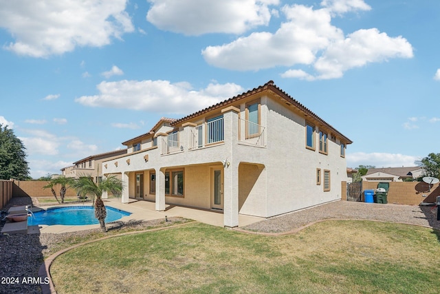 back of house with a patio, a fenced in pool, a balcony, and a lawn