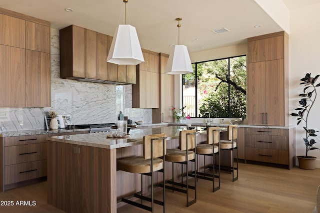 12887 N 135th St, Scottsdale, AZ 85259 - kitchen with modern cabinets, tasteful backsplash, a breakfast bar, light wood-style flooring, and recessed lighting