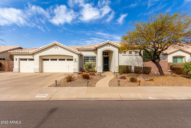 mediterranean / spanish-style house with driveway, an attached garage, a tile roof, and stucco siding