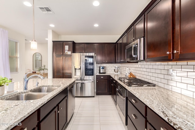 kitchen featuring sink, appliances with stainless steel finishes, tasteful backsplash, light stone countertops, and decorative light fixtures