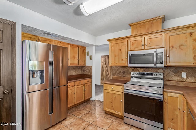 4020 W Anderson Dr, Glendale, AZ 85308 - kitchen with appliances with stainless steel finishes, light tile patterned floors, decorative backsplash, and a textured ceiling
