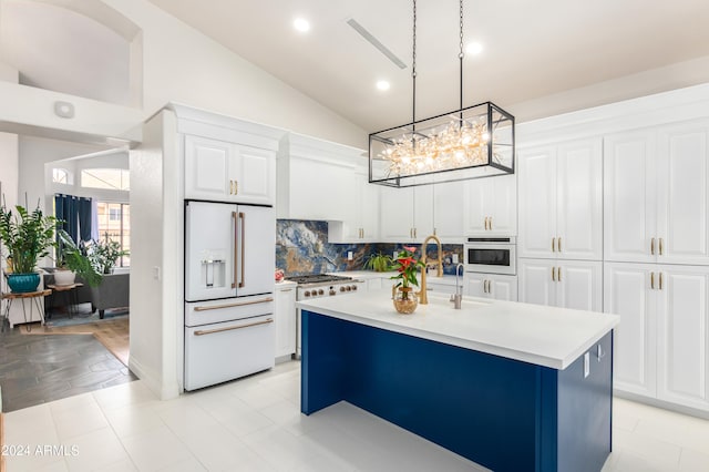 kitchen with decorative light fixtures, white appliances, an island with sink, and white cabinetry