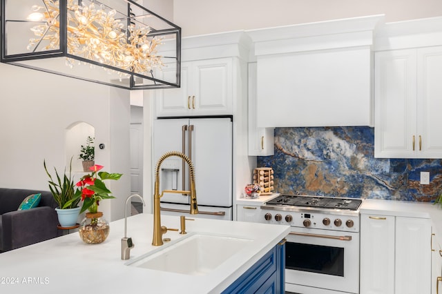 kitchen featuring pendant lighting, backsplash, white cabinets, and premium appliances