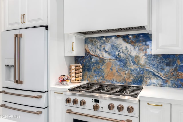 kitchen featuring custom exhaust hood, range, white cabinetry, and high end white refrigerator