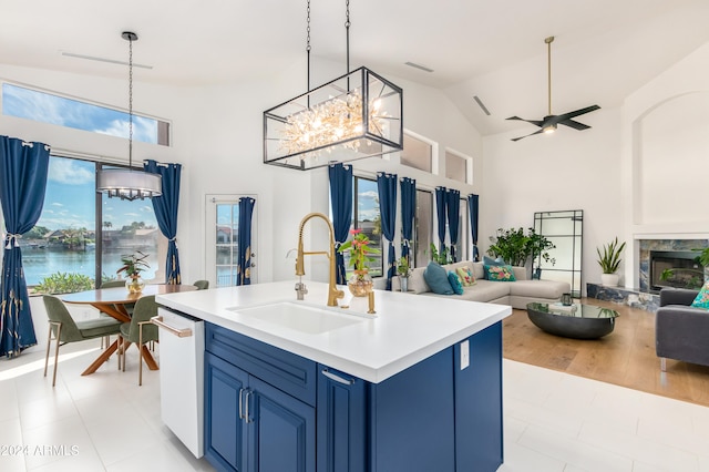 kitchen with decorative light fixtures, high vaulted ceiling, a center island with sink, dishwasher, and sink