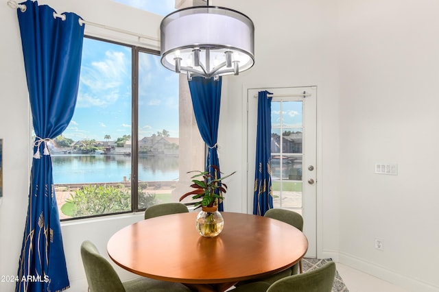 dining area with an inviting chandelier, a water view, and a wealth of natural light