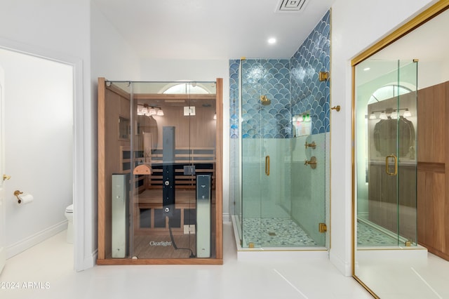 bathroom with toilet, tile floors, and a shower with door