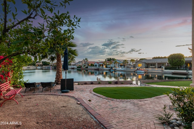 surrounding community with a patio, a water view, and a lawn