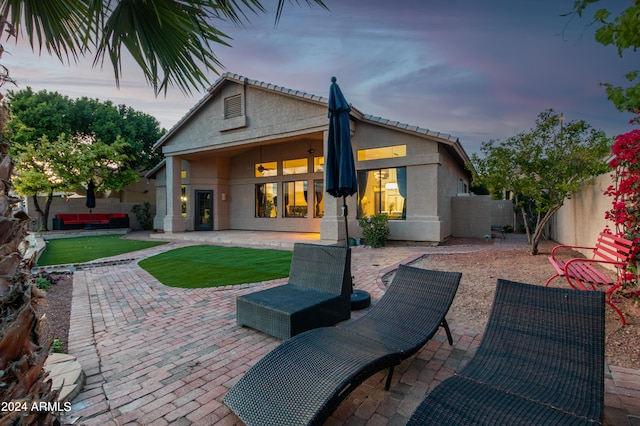 back house at dusk with a patio