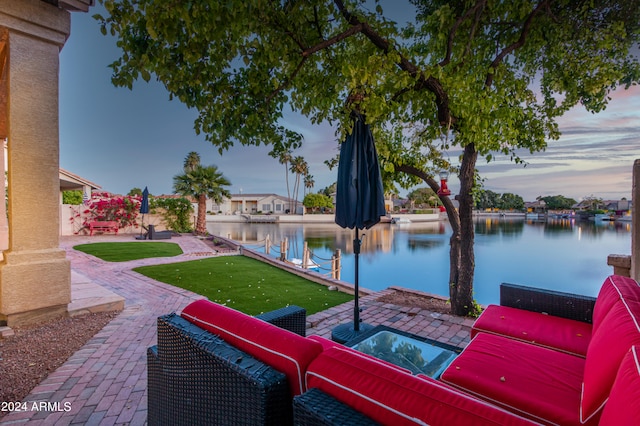 patio terrace at dusk featuring a water view and an outdoor living space