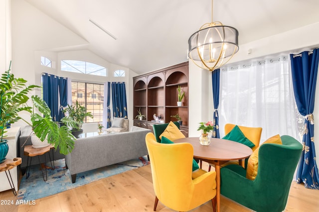 dining space with a notable chandelier, light wood-type flooring, and vaulted ceiling