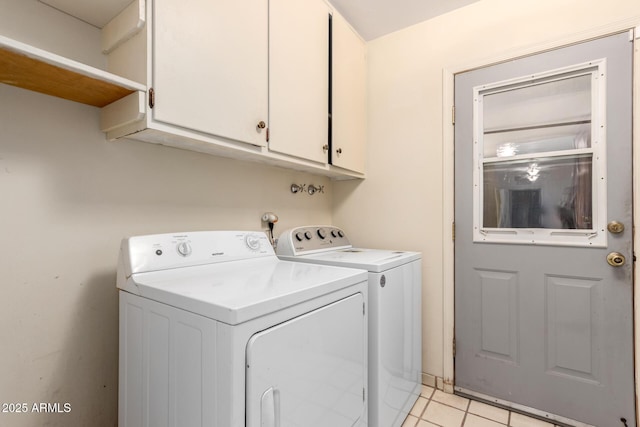 laundry area with light tile patterned floors, cabinets, and washing machine and clothes dryer