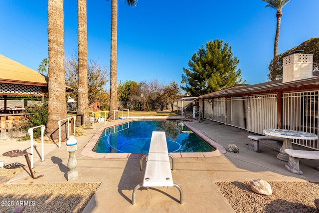 view of pool featuring a diving board and a patio area