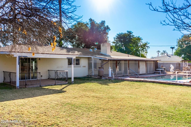 back of house featuring a pool side deck and a lawn