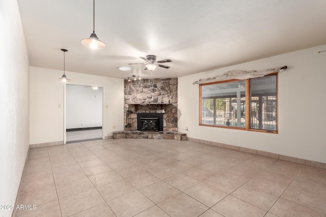 unfurnished living room with a stone fireplace, light tile patterned floors, and ceiling fan