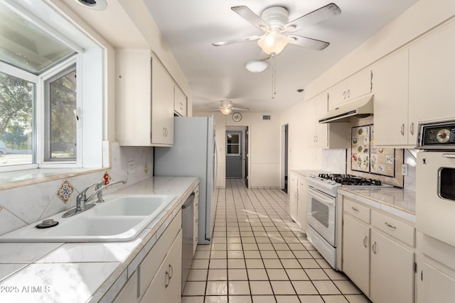 kitchen with tasteful backsplash, white cabinetry, sink, and white appliances