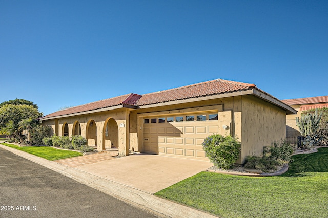 mediterranean / spanish-style home featuring a tiled roof, a front lawn, concrete driveway, and stucco siding