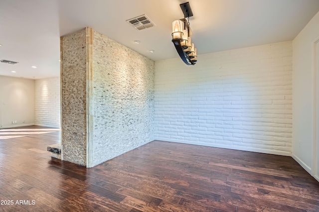 spare room with dark hardwood / wood-style floors and brick wall