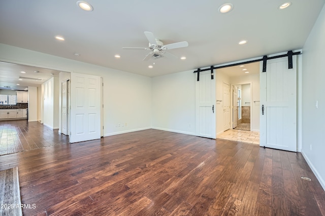 spare room featuring hardwood / wood-style floors, a barn door, and ceiling fan