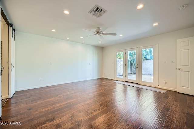 spare room with french doors, a barn door, dark hardwood / wood-style flooring, and ceiling fan