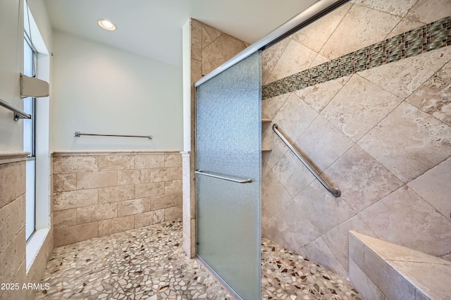 bathroom with a tile shower and tile walls