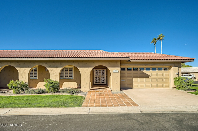 mediterranean / spanish-style home featuring a garage, driveway, a tiled roof, and stucco siding