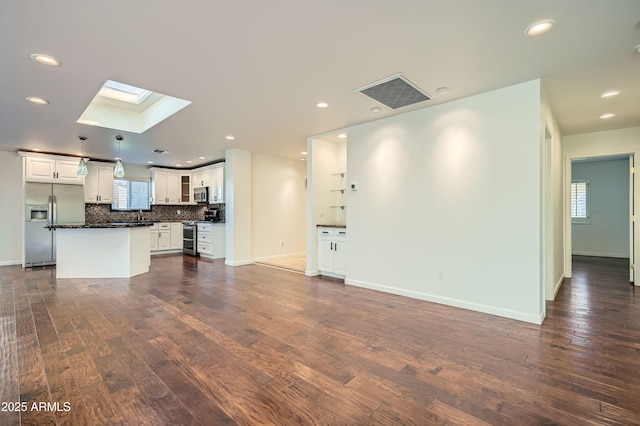 unfurnished living room featuring a skylight and dark hardwood / wood-style floors