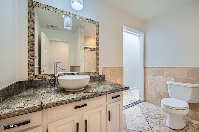 bathroom with vanity, tile walls, and toilet