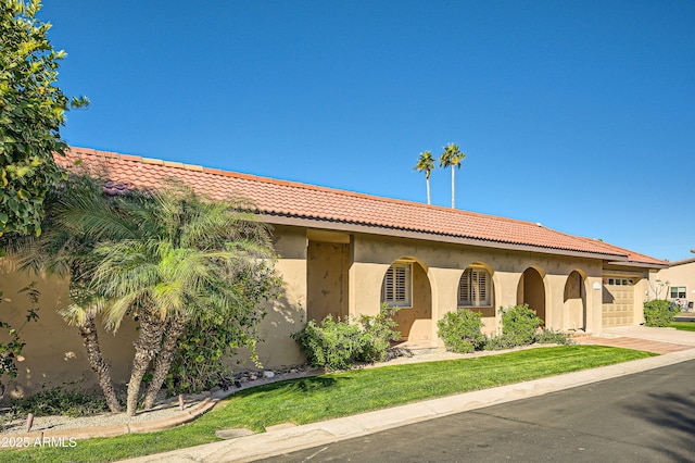 mediterranean / spanish-style house featuring a garage, a front yard, a tile roof, and stucco siding