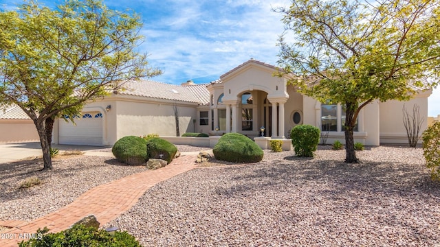 mediterranean / spanish-style house with a garage, a tiled roof, concrete driveway, and stucco siding