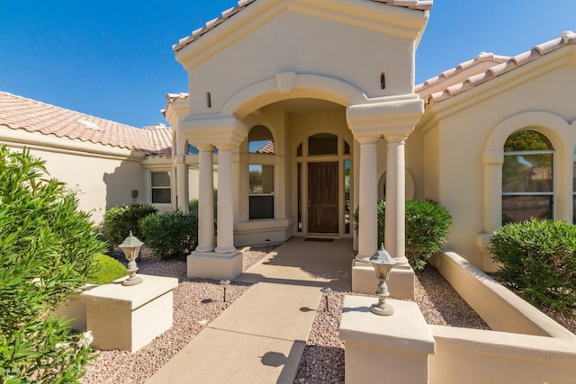 entrance to property featuring a tile roof and stucco siding