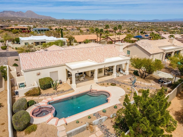 view of swimming pool with a pool with connected hot tub, a patio area, a fenced backyard, and a mountain view