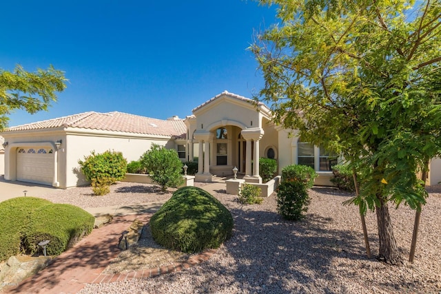 mediterranean / spanish home with a garage, a tile roof, and stucco siding