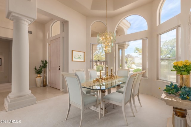 dining area featuring a notable chandelier, light colored carpet, a towering ceiling, and ornate columns