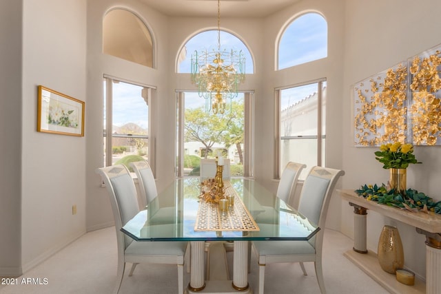 dining room with baseboards, carpet flooring, a notable chandelier, and a high ceiling