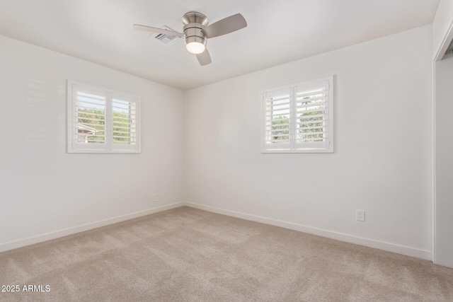 spare room featuring a ceiling fan, light colored carpet, visible vents, and baseboards