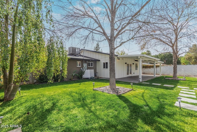 back of property featuring a yard, central AC unit, board and batten siding, a patio area, and fence