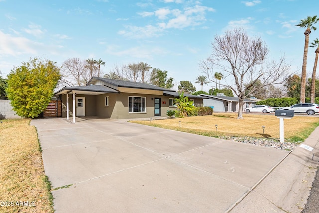 view of front of house featuring driveway, a front lawn, fence, and an attached carport