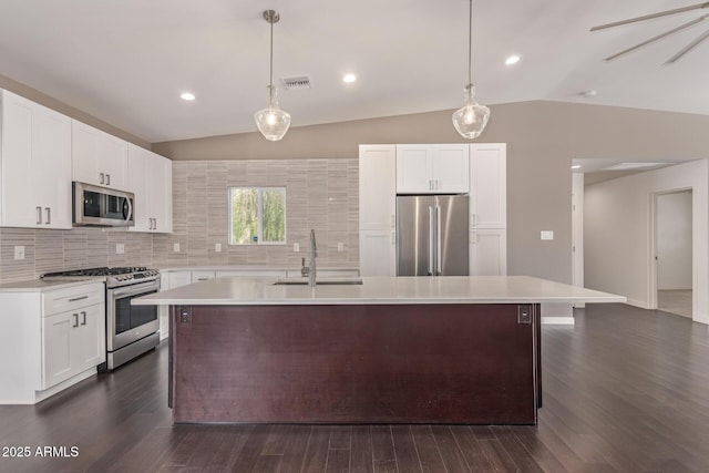 kitchen with appliances with stainless steel finishes, vaulted ceiling, light countertops, and a sink