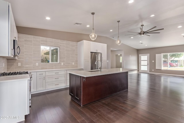 kitchen featuring visible vents, open floor plan, stainless steel appliances, light countertops, and a sink