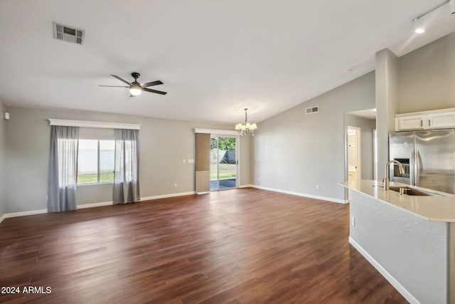 unfurnished living room featuring ceiling fan with notable chandelier, a healthy amount of sunlight, sink, and dark wood-type flooring