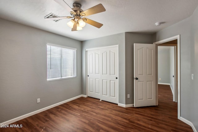 unfurnished bedroom with ceiling fan, dark hardwood / wood-style flooring, and a closet