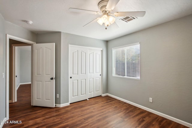 unfurnished bedroom with a closet, ceiling fan, and dark wood-type flooring