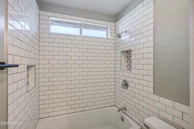 bathroom featuring tiled shower / bath combo and toilet