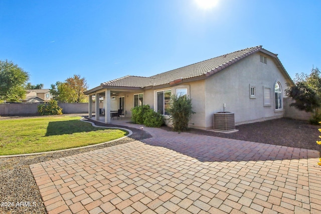 rear view of house with central AC unit, a yard, and a patio