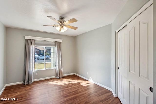 unfurnished bedroom featuring ceiling fan, dark hardwood / wood-style flooring, and a closet